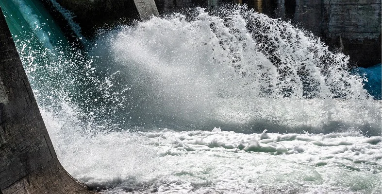 The transaction will give TotalEnergies an interest in hydropower projects in Uganda, Rwanda and Malawi A close up of water cascading out of a hydropower plant.